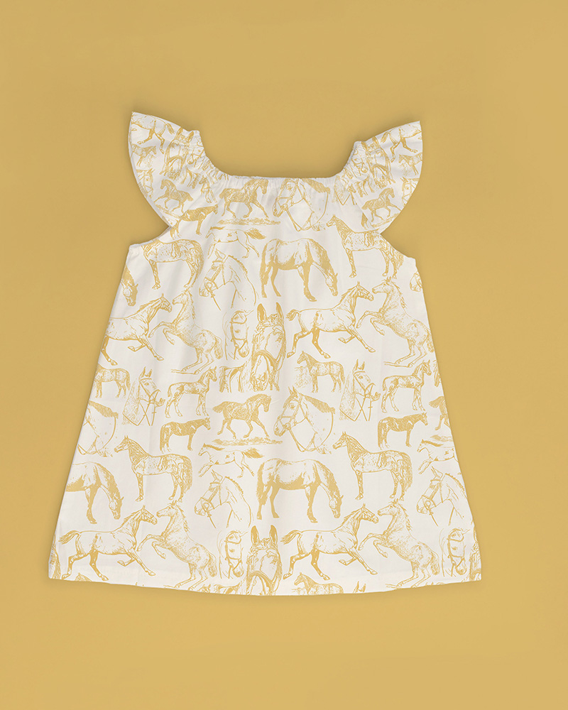 Image of a little girl's dress in "For the Love of Horses" Pattern in Stone and Gold.