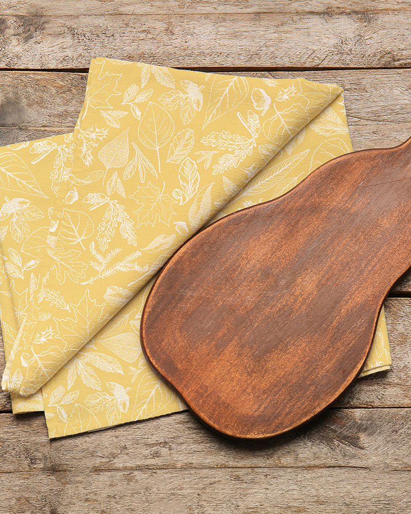 Image of a tea towel featuring the Foliage design in Gold and Stone.