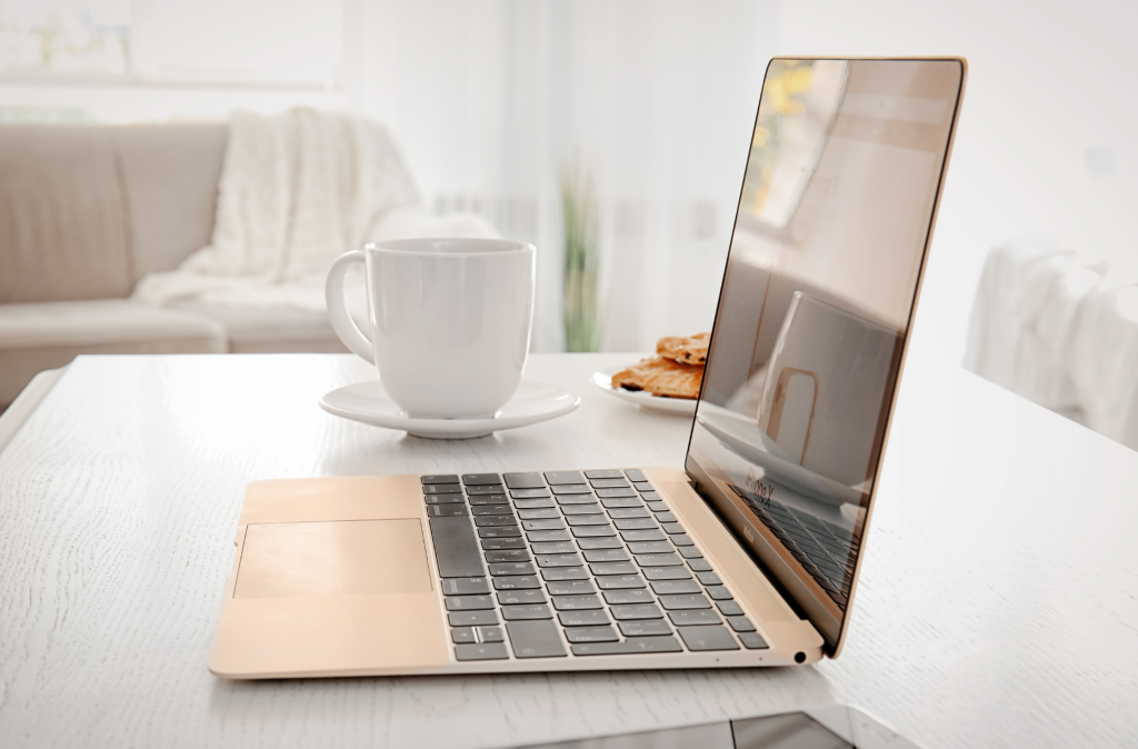 Image of an open rose gold coloured laptop on a coffee table.