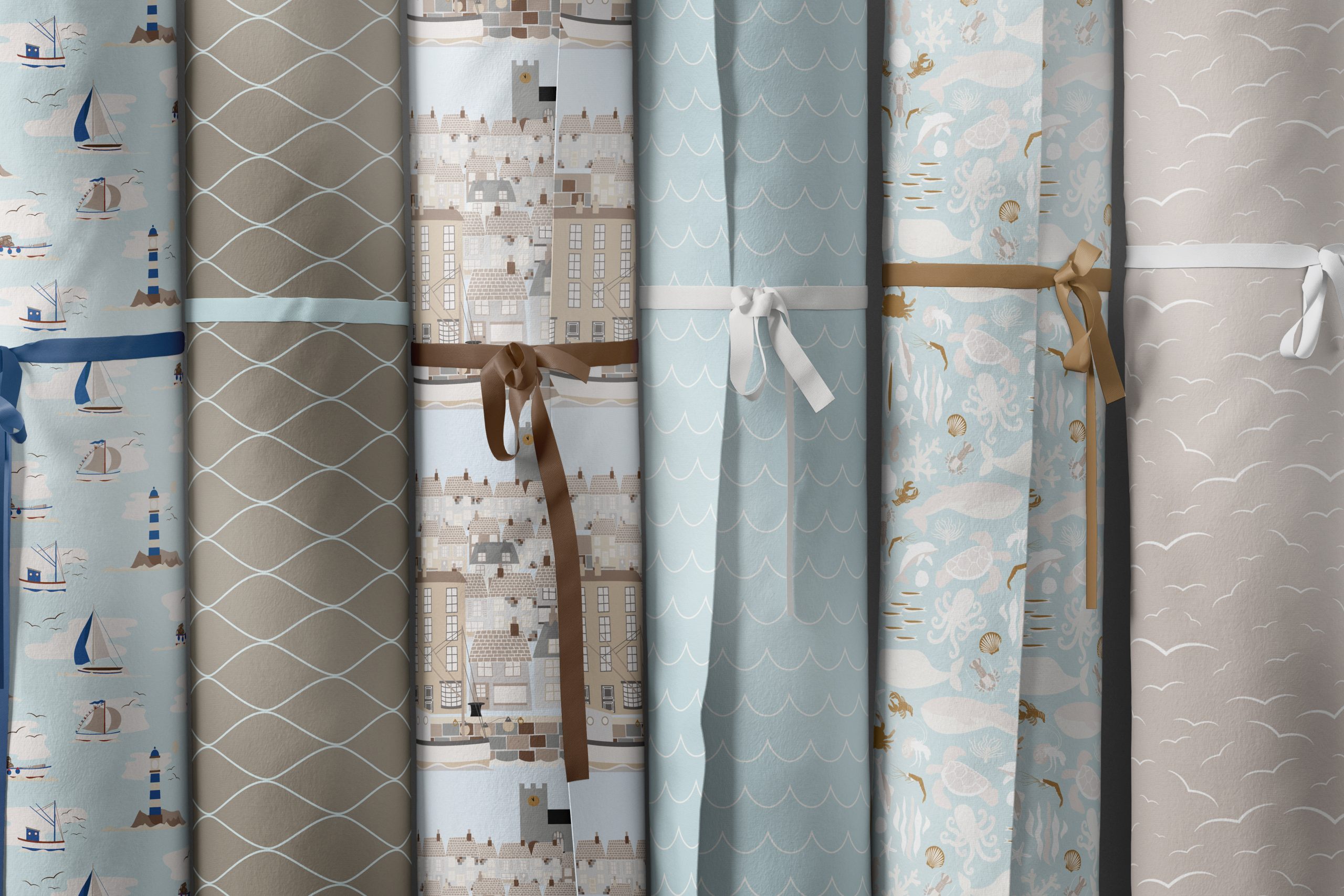 Image showing six fabric bolts each tied with ribbon, all featuring patterns from the Quayside collection created by Seaweed & Spruce.