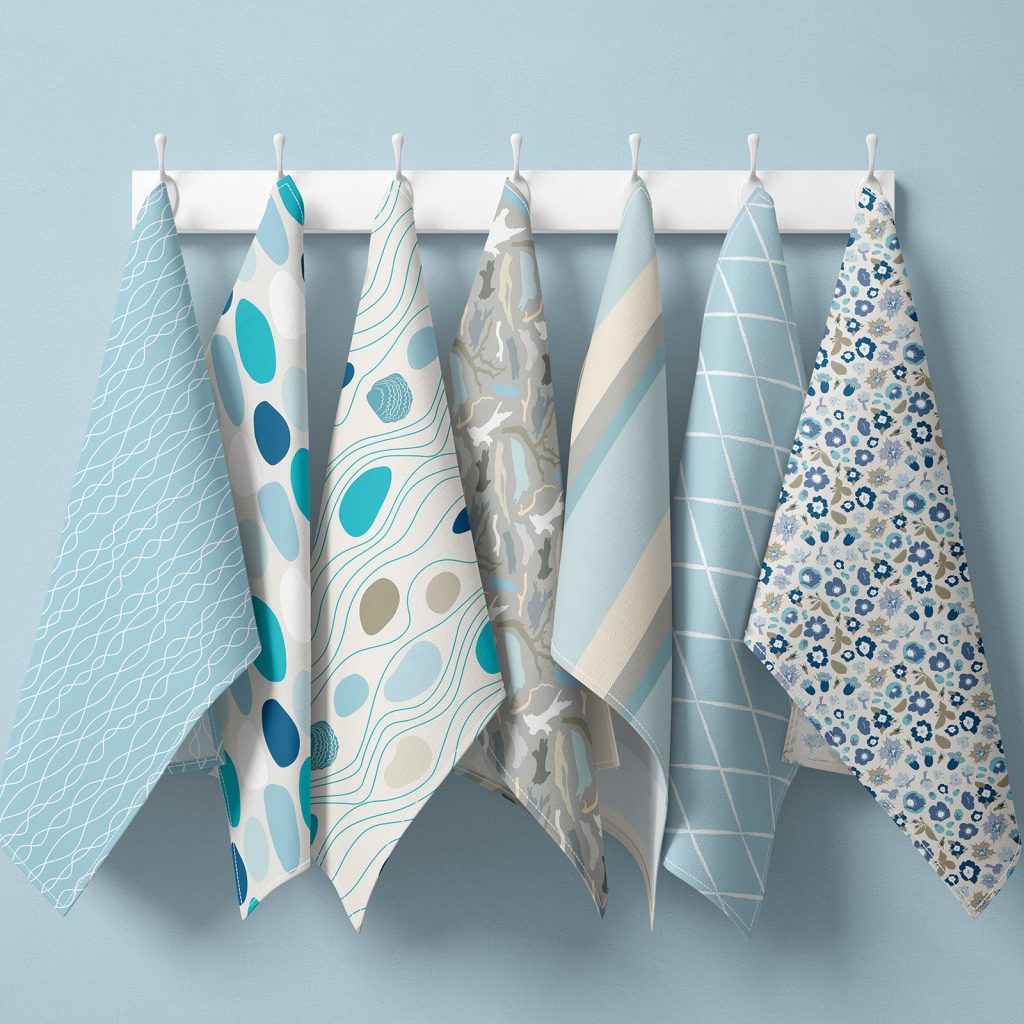An image of seven hanging tea towels all featuring designs from the Sennen collection in the Blue Hues colourway.