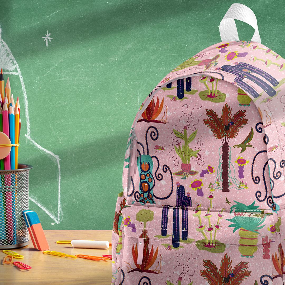 Image of a backpack featuring Seaweed & Spruce's Other Worldly "Creatures" pattern. The backpack is sitting on a desktop in front of a green chalkboard.